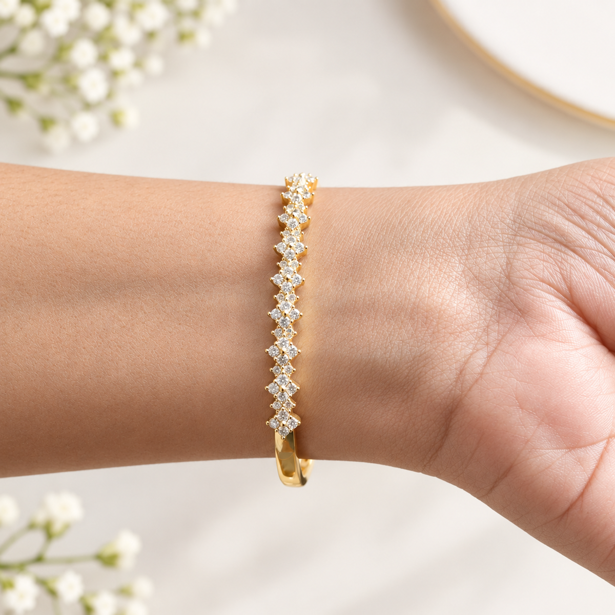Close-up of a golden bangle bracelet featuring channel-set baguette crystals and screw-motif accents worn on a wrist.